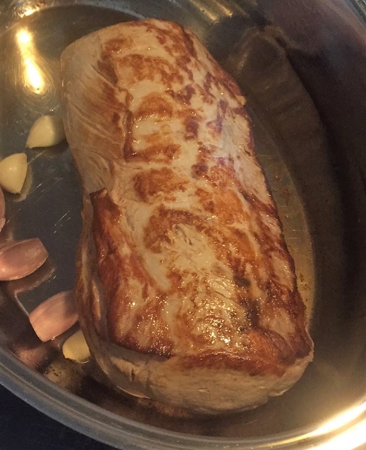 Ein bedeckter Schweinebraten auf einem weißen Becher